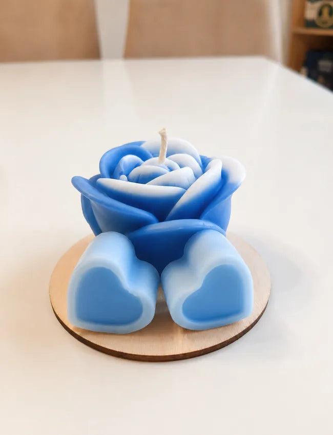 Blue rose candle with two blue heart wax melts on a round wooden base