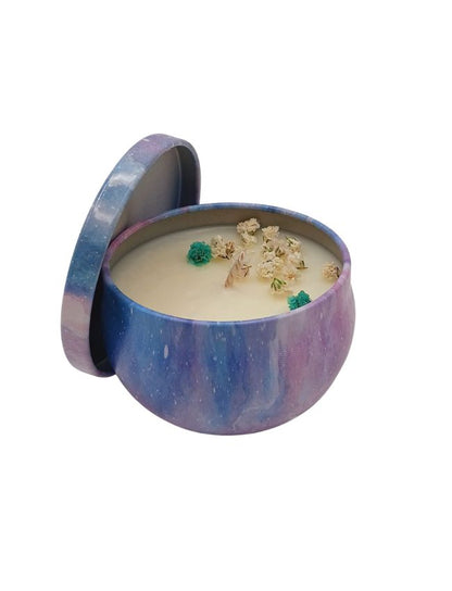 Candle in a decorative purple and blue container with floral elements on a white background
