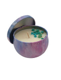 Candle in a decorative purple container with flowers on a white background