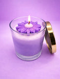 Purple candle in a glass jar with a gold lid on a purple background