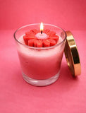 Pink candle in a glass jar with a floral center on a pink background