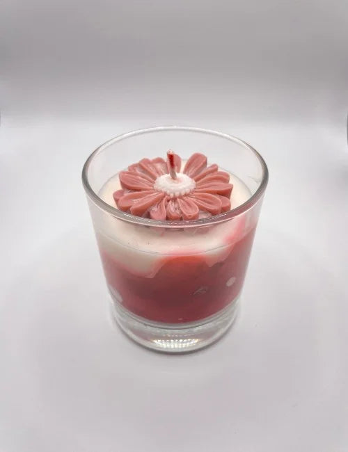 soy candle with a brown and white layered design and a floral wax adornment.