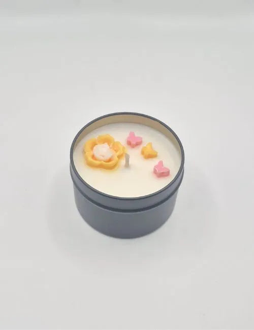 Soy candle in a gold tin with orange flower decorations and an invigorating citrus aroma.