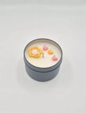 Soy candle in a gold tin with orange flower decorations and an invigorating citrus aroma.