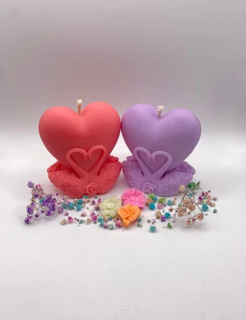Heart-shaped soy candles in red and purple, arranged with decorative flowers.