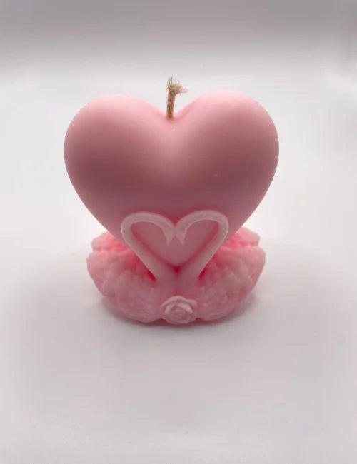 Heart-shaped soy candle in soft pink, sitting on a detailed rose and swan base.