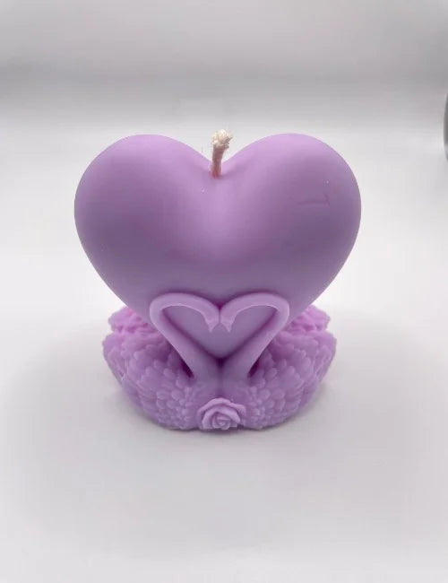 Purple heart-shaped soy candle with intricate swan and rose detailing at the base.