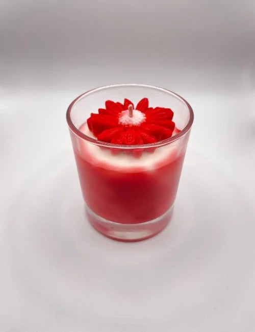 Soy candle with a bold red and white layered design and a delicate floral wax accent.