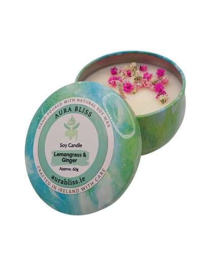 Soy candle in a decorative tin with lemongrass and ginger scent, branded 'Aura Bliss'.