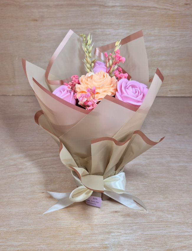 Pink floral soy wax candle arrangement in brown paper wrap.
