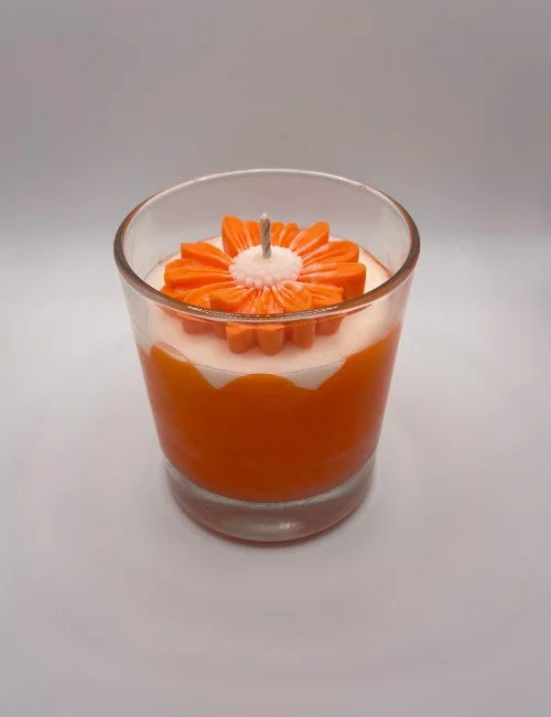 Soy candle featuring a red and white layered design with a floral wax topper.