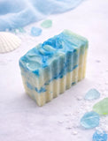 Blue and green swirled soap bar on a white background with seashells.