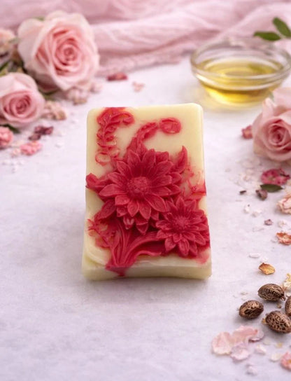 Bar of soap with floral design surrounded by pink roses and petals on a light background