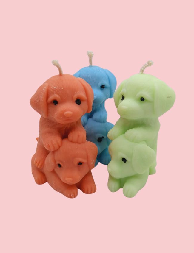 Colorful dog-shaped candles on a pink background