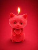Handmade red cat soy wax candle by Aura Bliss with a lit wick on a rich red background
