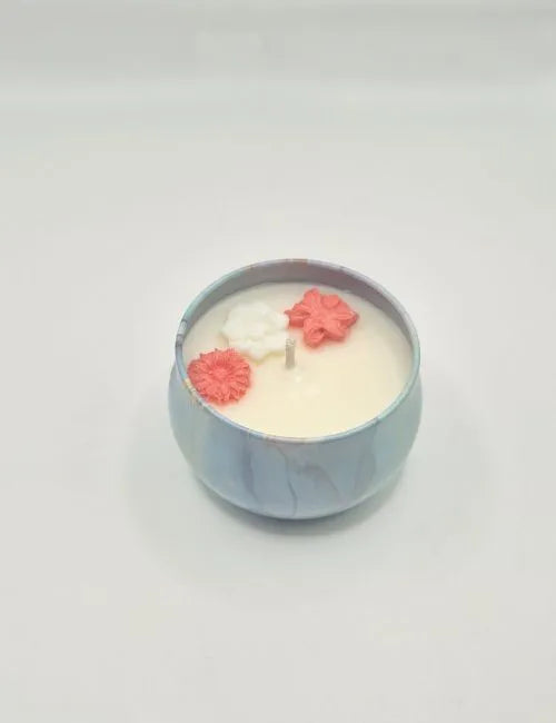 Soy candle in a light blue tin adorned with rose-shaped wax decorations and a romantic rose scent.