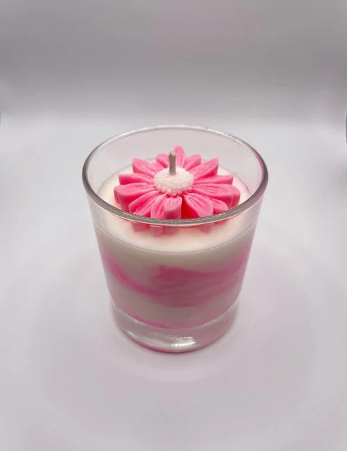 soy candle with a vibrant orange and white layered design and a flower-shaped wax detail.