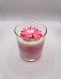 soy candle with a vibrant orange and white layered design and a flower-shaped wax detail.