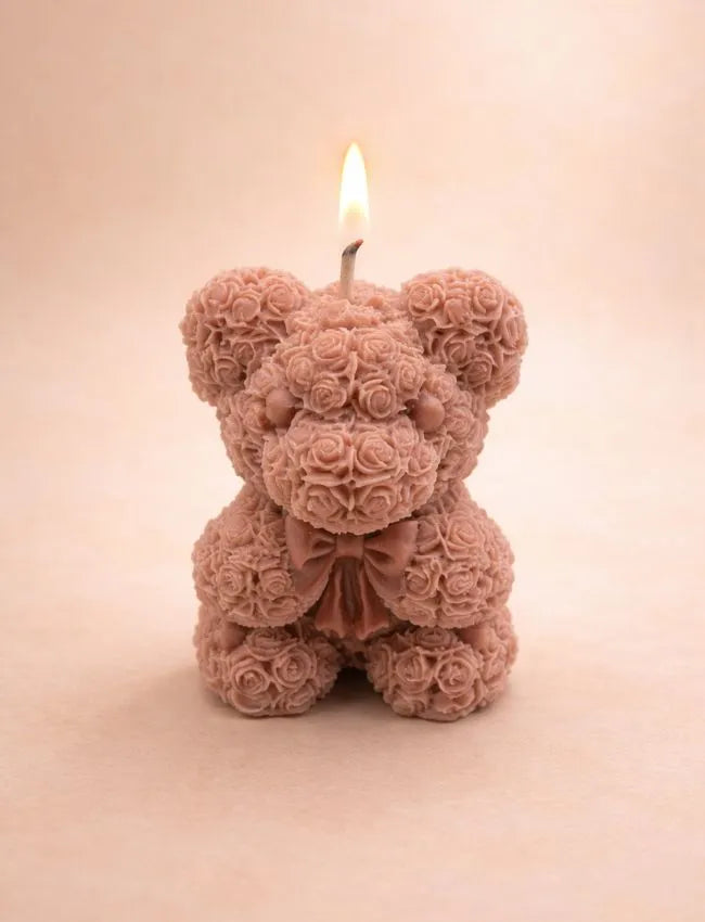 Handcrafted teddy bear soy wax candle by Aura Bliss with a lit wick on a soft neutral background