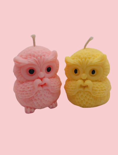 Two owl-shaped candles, one pink and one yellow, on a pink background.