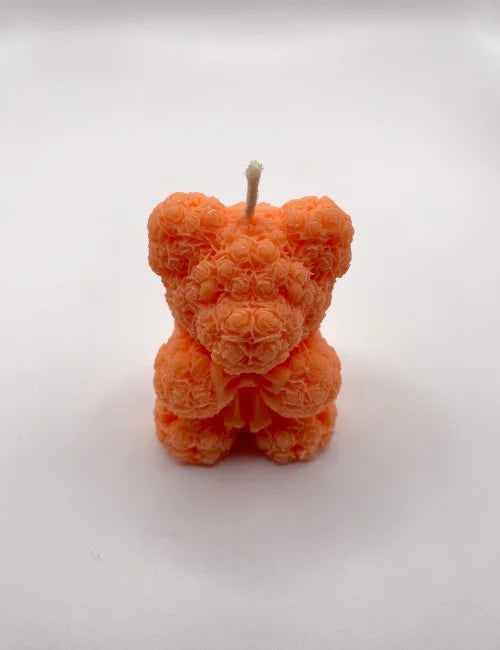 A bright orange Bear Scented Candle with rose accents, bringing a lively touch to any room or occasion.
