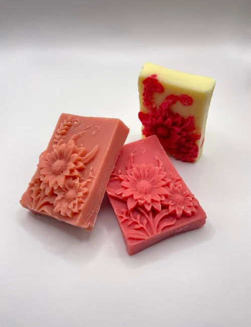 A collection of Blooming Rose soaps with intricate floral designs, available in pink and yellow-red variations.