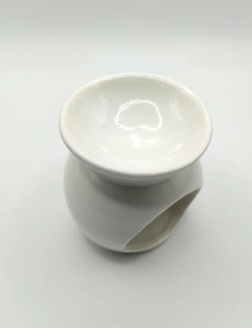 Side view of a white ceramic wax burner with an open tealight space.