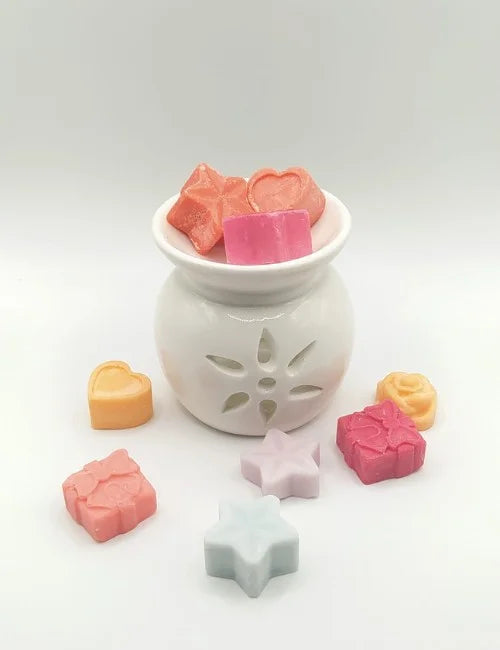 White ceramic wax burner with colorful wax melts on top.