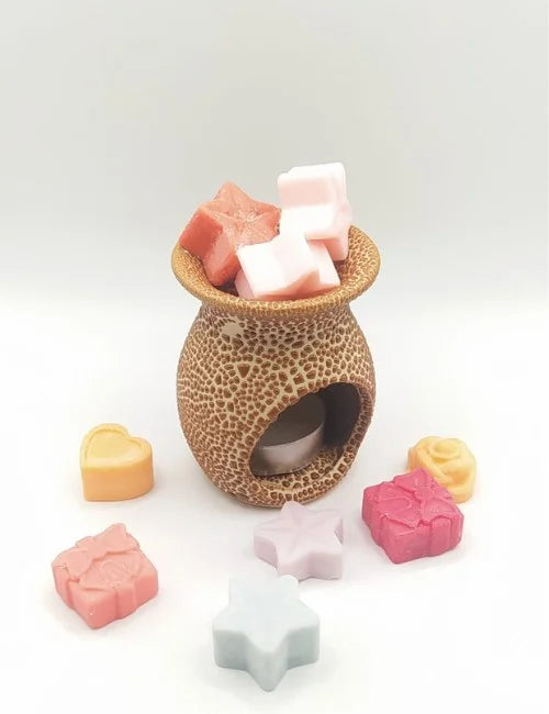 Wax burner with assorted wax melts in warm tones.