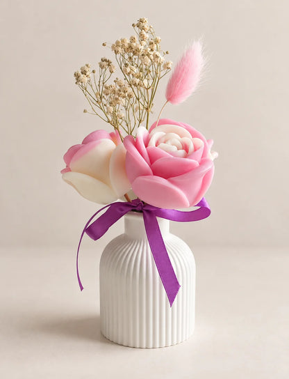 Close-up of handcrafted wax rose bouquet in white ribbed vase with purple ribbon