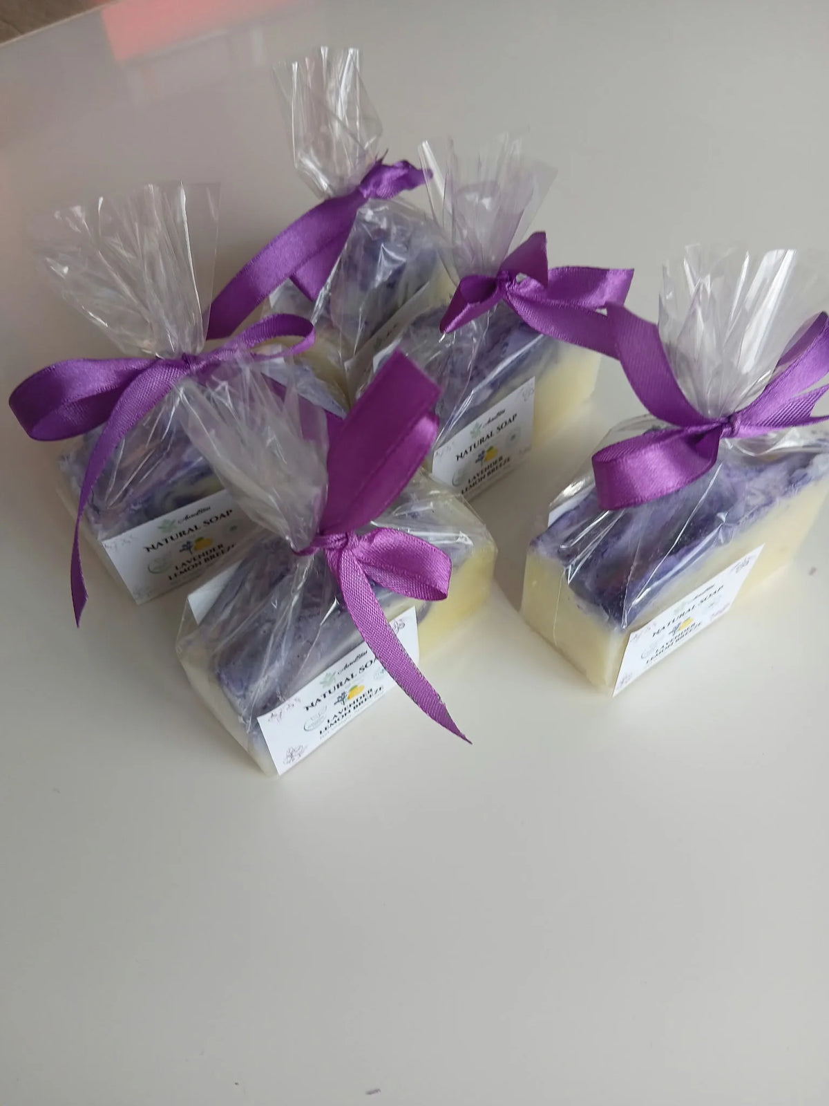 Four individually wrapped soap bars tied with purple ribbons