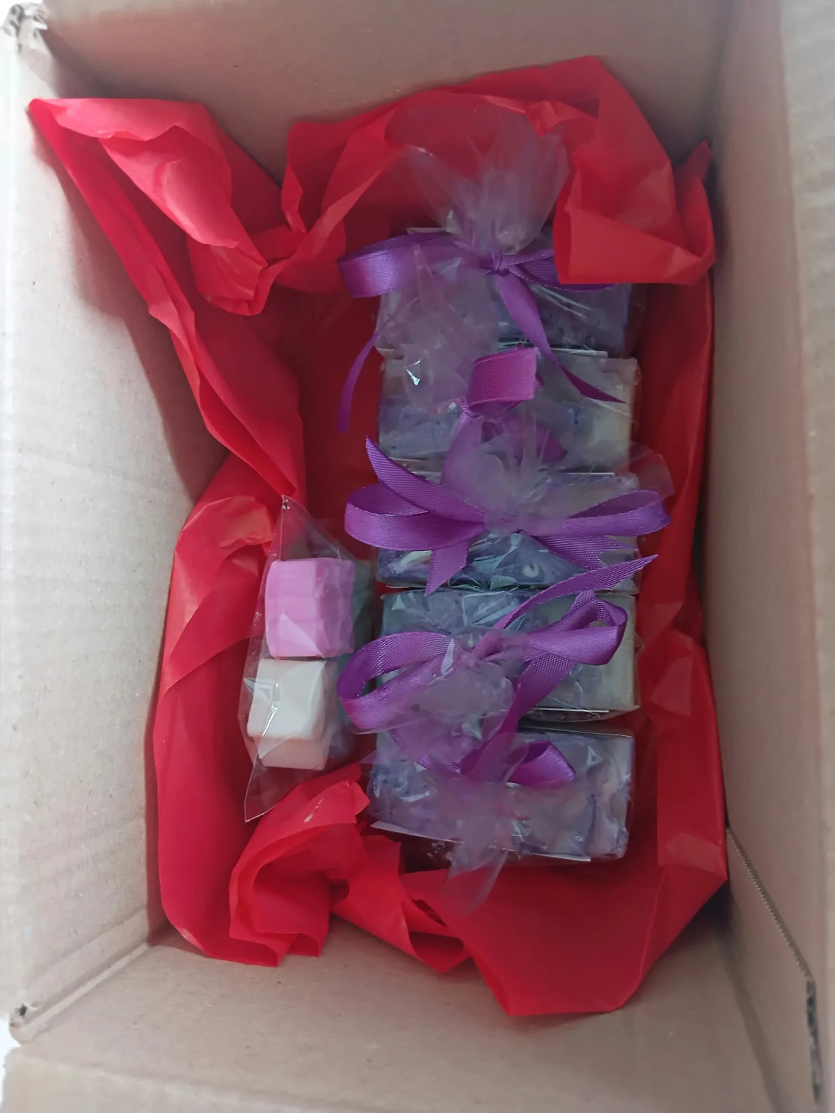 Individually wrapped soap bars packed in a cardboard box with red tissue paper