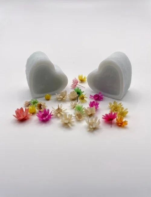 Blue natural wax melts shaped like hearts, surrounded by colorful dried flowers.