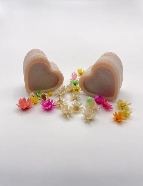 Brown natural wax melts shaped like hearts, surrounded by colorful dried flowers.