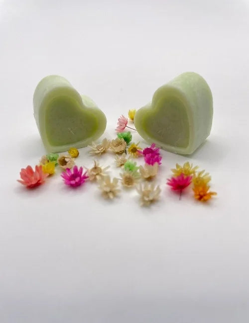 Green natural wax melts shaped like hearts, surrounded by colorful dried flowers.