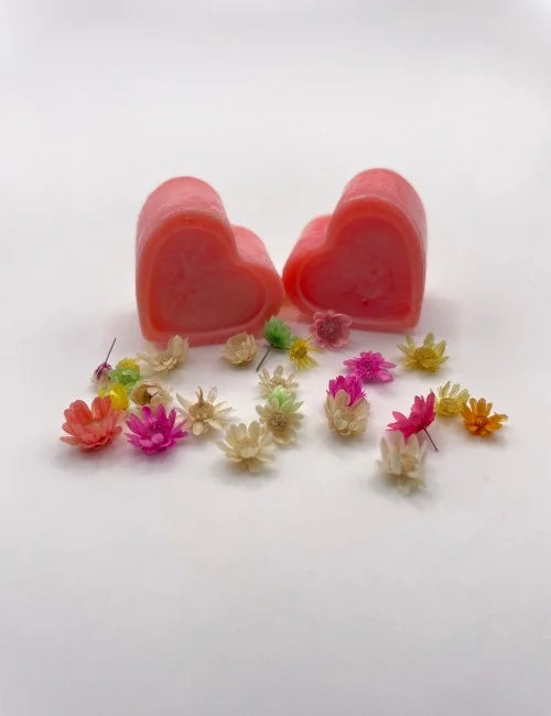 Red natural wax melts shaped like hearts, surrounded by colorful dried flowers.