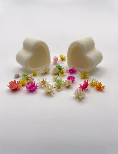 White natural wax melts shaped like hearts, surrounded by colorful dried flowers.
