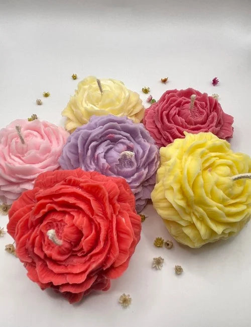 A group of six natural candles in various colors, including yellow, pink, purple, and red, all shaped like roses.