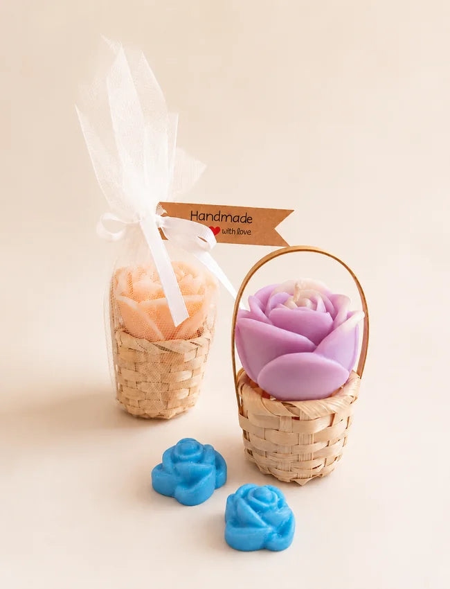 Rose candle in a small woven basket with two flower wax melts and gift-wrapped basket behind