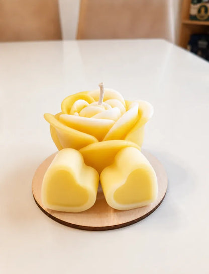 Yellow rose candle with two yellow heart wax melts on a round wooden base