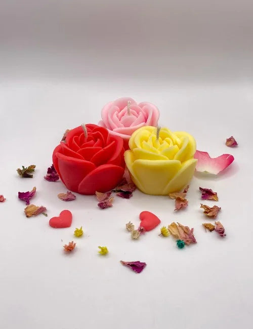 A group of rose-shaped candles in vibrant colors, surrounded by dried petals, perfect for romantic decor and gifting.