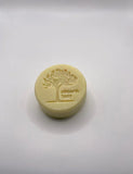 A yellow Simply Natural round soap featuring a tree stamp, perfect for gentle and hydrating skincare.