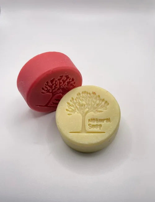 A pair of Simply Natural round soaps in red and yellow, stamped with a tree design, perfect for nourishing and gentle skincare.