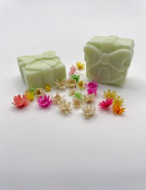 Fresh green wax melt gift box surrounded by colorful flowers.