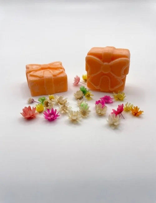 Orange wax melt gift box arranged with natural flowers.