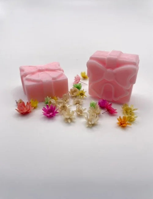 Gentle pink wax melt gift box alongside small flowers.