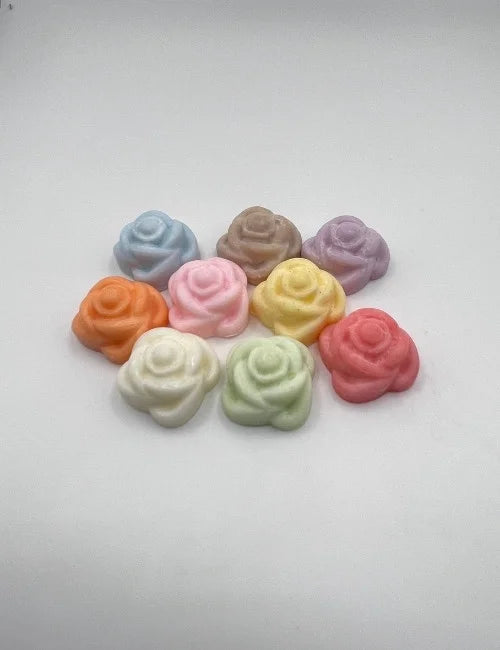 Assorted rose-shaped wax melts in vibrant colors arranged with colorful dried flowers.