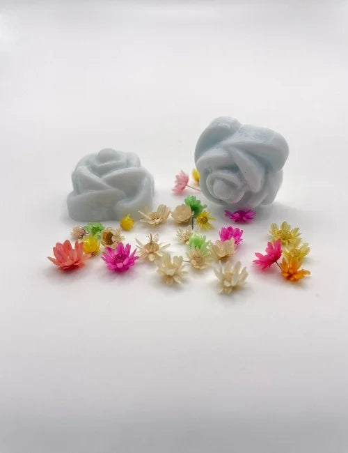 Blue rose-shaped wax melts surrounded by colorful dried flowers.