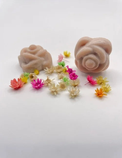 Brown rose-shaped wax melts surrounded by colorful dried flowers.