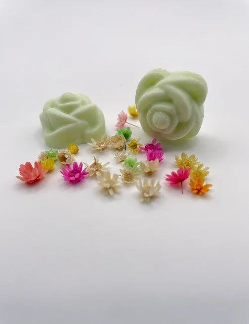 Green rose-shaped wax melts surrounded by colorful dried flowers.